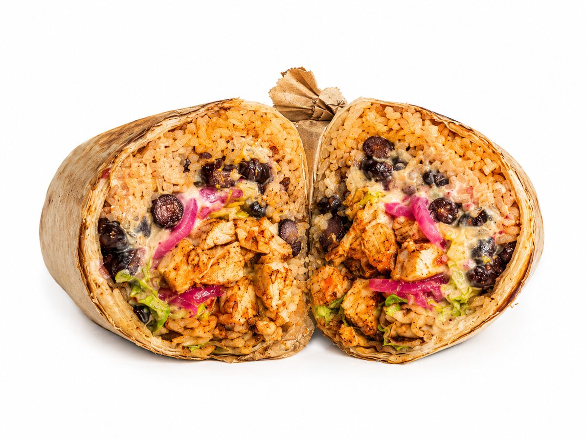 Nachoz signature burrito sliced in half showing rice, beans, protein and melted cheese